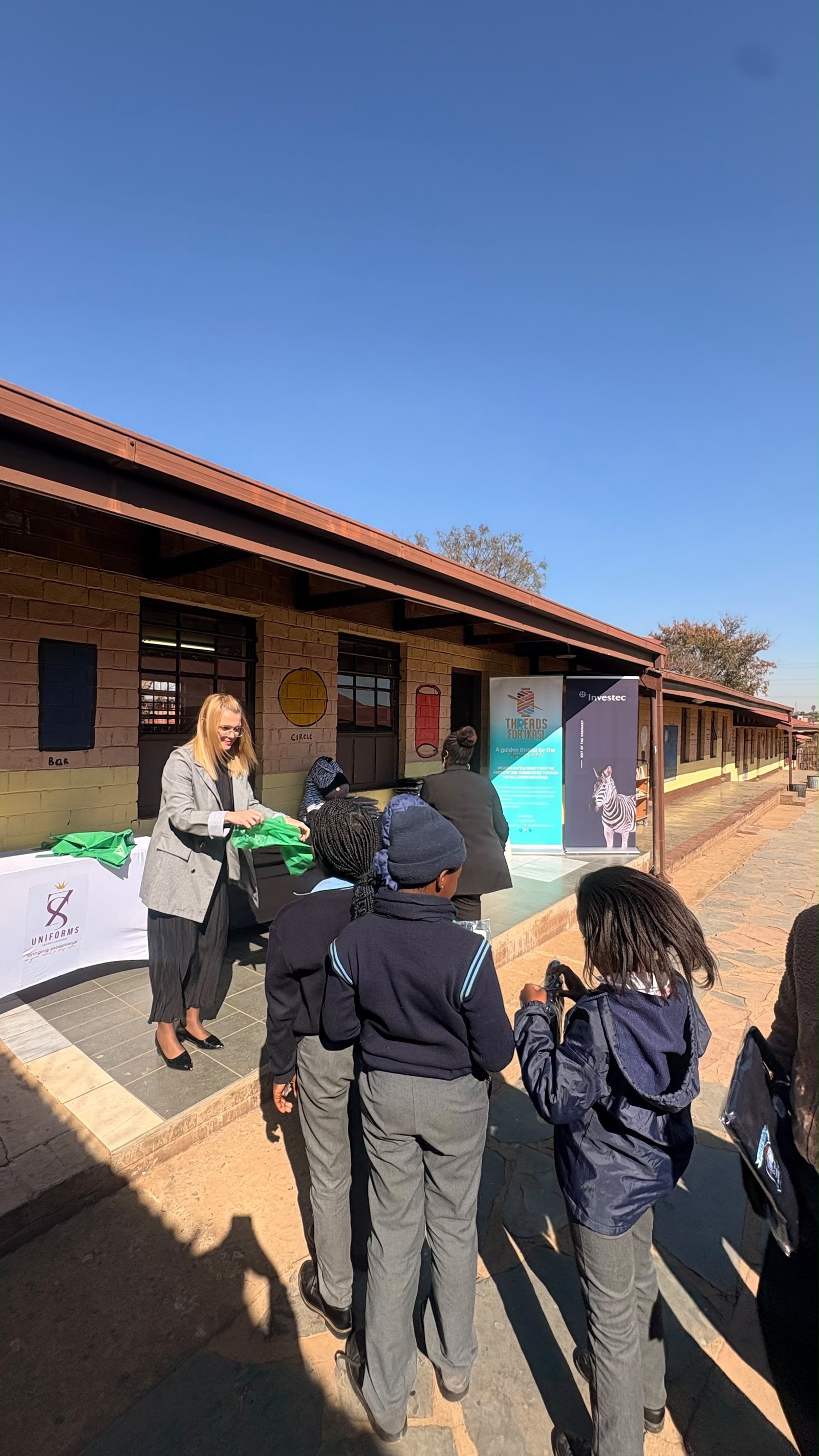 An Investec representative handing a school jersey to a learner at Sindawonye Primary School
