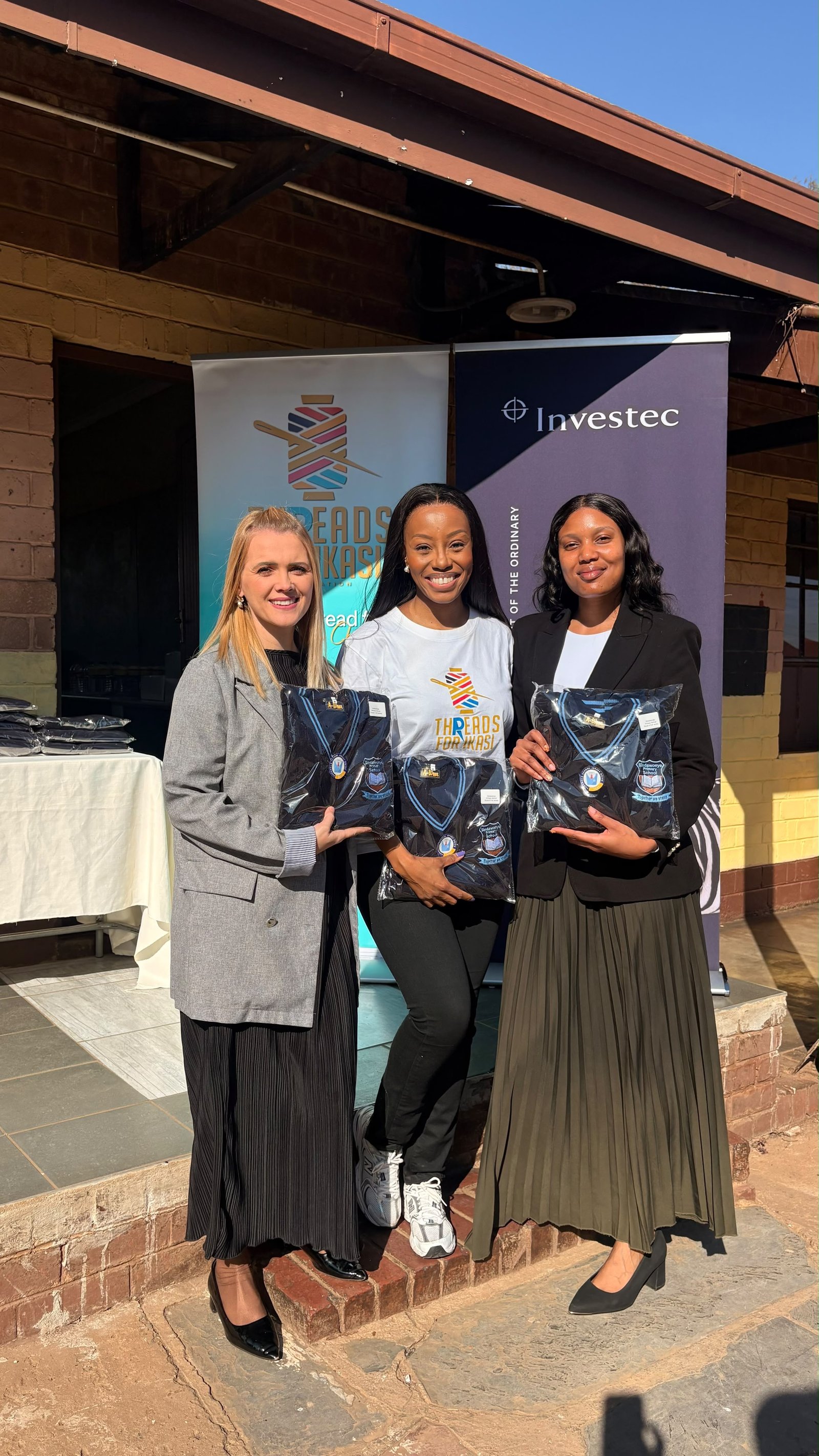 Representatives from Threads for iKasi Foundation and Investec holding Sindawonye Primary School jerseys at the handover